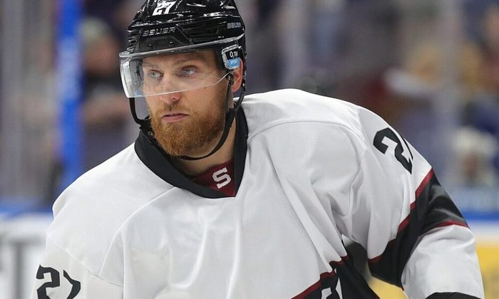 Eishockeyspieler mit Bart und Nummer 27 im Spiel in einer Halle.